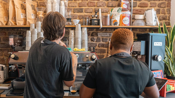 Coffee training session with two people facing a coffee machine making espressos